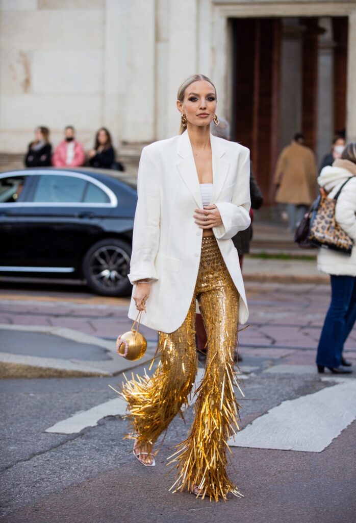 Moteris dėvinti baltą švarkelį ir auksines kelnes