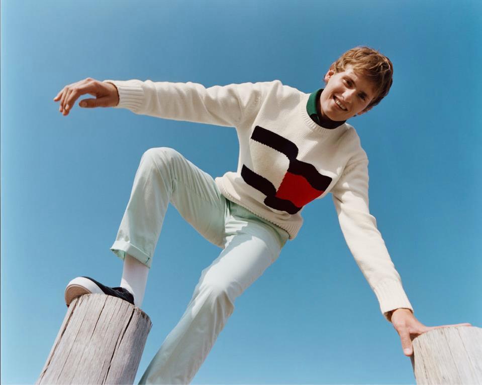 Vyras, dėvintis baltą Tommy Hilfiger megztinį ir šviesias kelnes