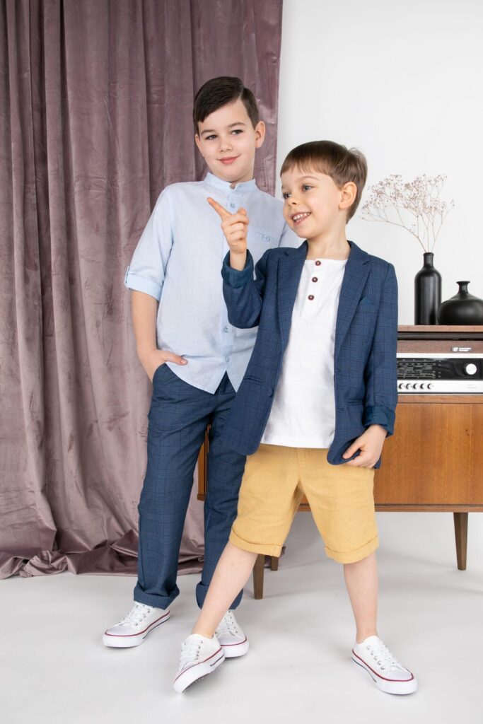 Du berniukai, dėvintys marškinėliais, elegantiškomis kelnėmis ir sportbačiais