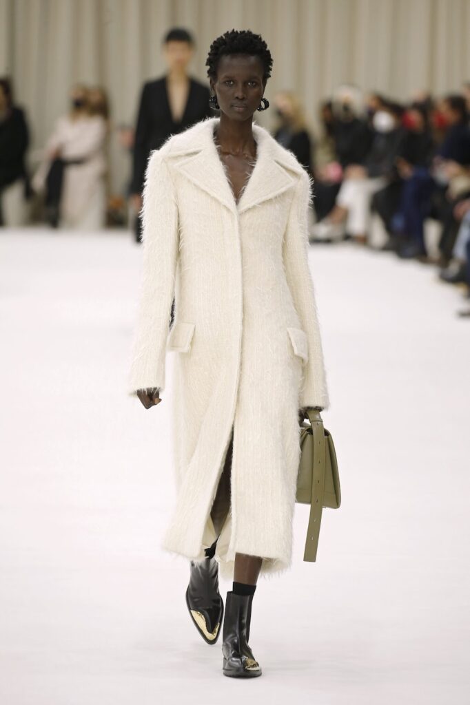 Modelis, dėvinti ilgą baltą paltą