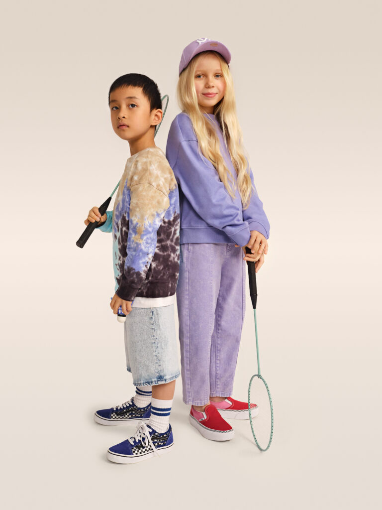 Mergaitė ir berniukas, dėvintys violetinio atspalvio drabužius ir Vans sportbačius