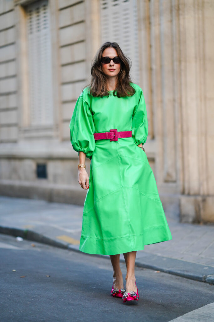 Moteris, dėvinti žalią suknelę ir fuksijų rožinės spalvos aukštakulnius batelius