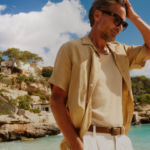vyras paplūdimyje dėvi šviesias kelnes ir lininius marškinius trumpomis rankovėmis